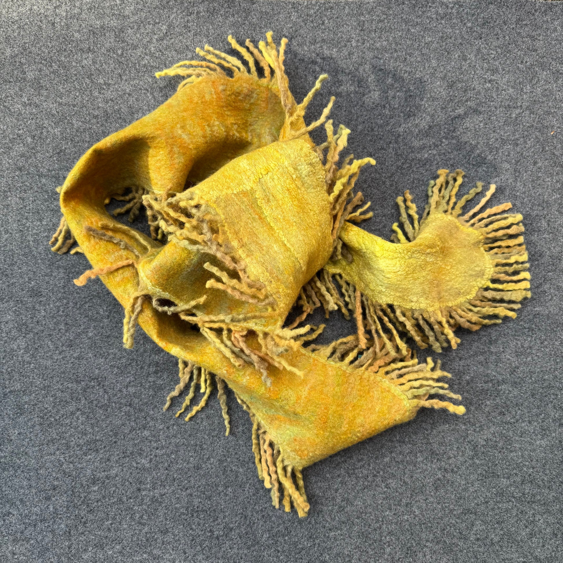 Yellow scarf with fringes on a gray background
