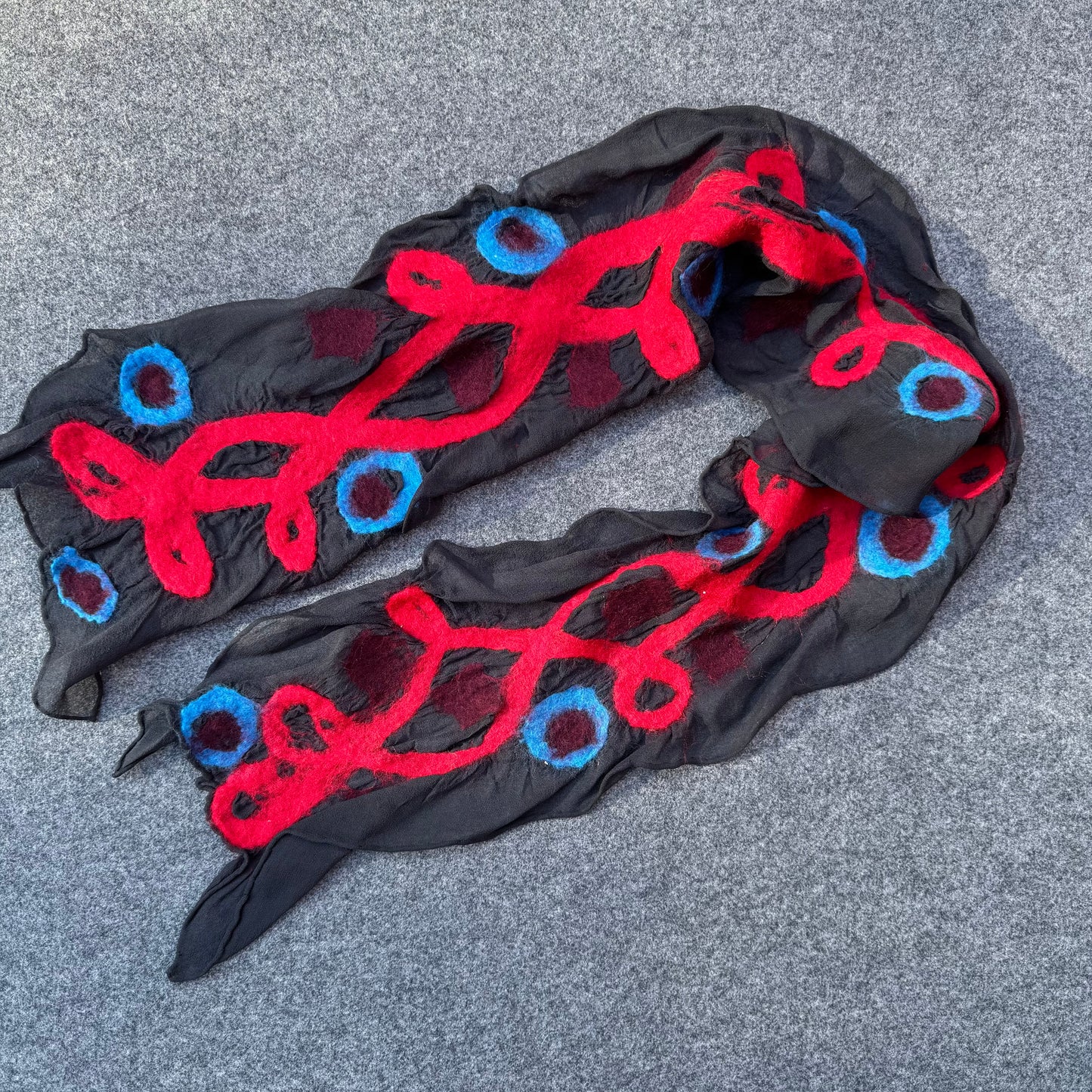 Black scarf with red and blue patterns on a gray surface