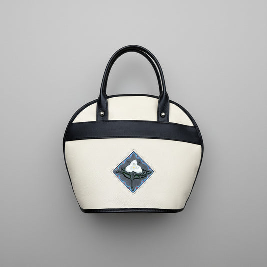 White handbag with black handle and trillium embossed design and handpainted on on leather