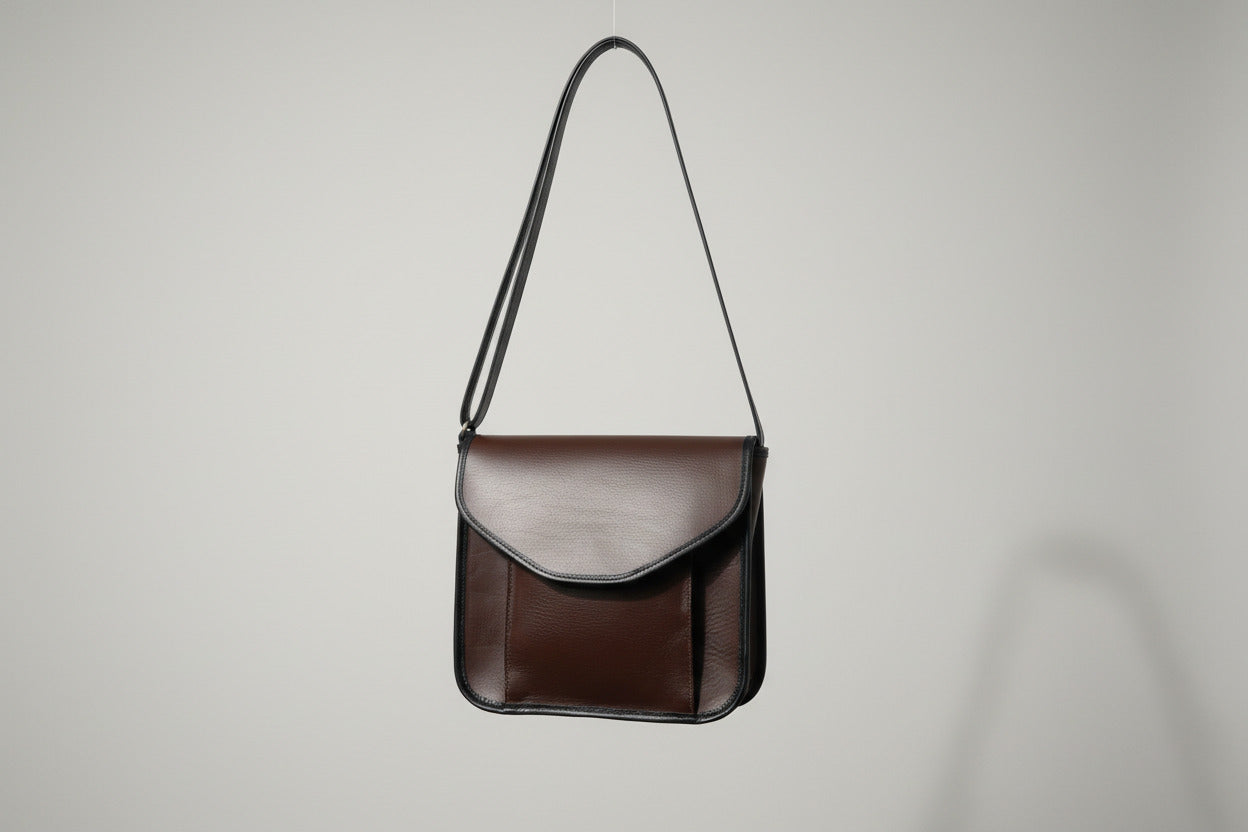 A brown leather crossbody bag with an adjustable strap, handmade in Door County, WI